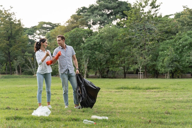 Casal de amantes voluntários usando luvas caminhando para pegar lixo no parque