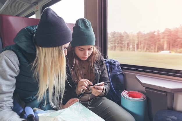 Casal de amigas olhando para o smartphone enquanto no trem