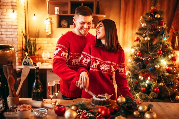 Casal de amor feliz prova bolo de Natal, comida festiva. Celebração de Natal juntos, jovem felicidade familiar