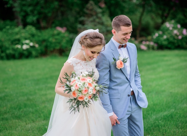 Casal de casamento deslumbrante caminha sob árvores florescendo no parque