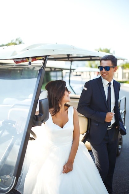 Casal de casamento elegante de luxo se beijando abraçando perto de carro para jogar golfe Juntos Família jovem Casamento