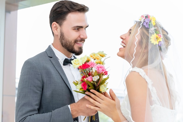 Casal de caucasiano, noivo dá noiva atual no estúdio de casamento.