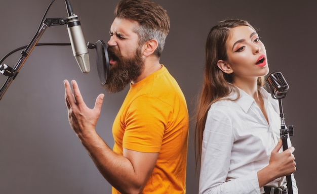 Casal de dueto de cantor está tocando uma música com microfone durante a gravação em um estúdio de música