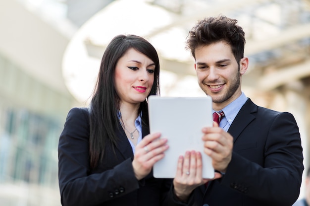 Casal de empresários usando um tablet ao ar livre