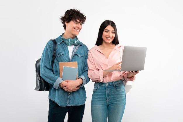 Casal de estudantes alegres usando laptop para educação sobre fundo branco