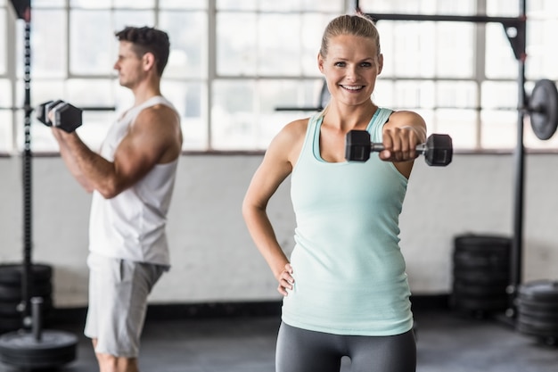 Casal de exercício com halteres na academia