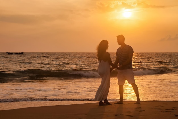 Casal de família adorável adulto de mãos dadas relaxando no fundo do pôr do sol do oceano Homem e mulher em roupas casuais caminhando juntos na praia ao ar livre