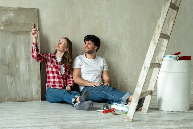 Foto casal de família feliz relaxando depois de pintar um jovem casal deitado no chão de uma casa nova e se comunicando