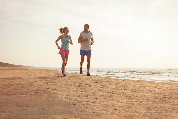 Casal de fitness feliz correndo na praia