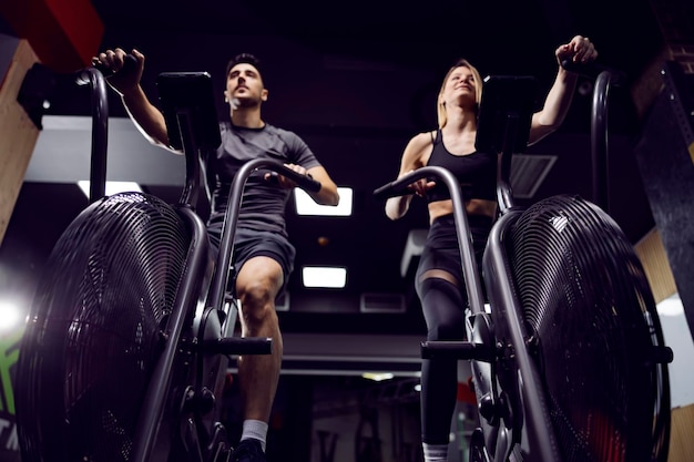 Casal de fitness praticando na bicicleta ergométrica em uma academia