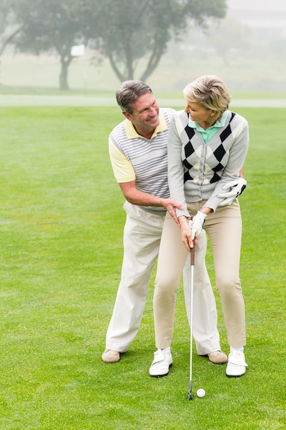 Casal de golfe colocando bola juntos