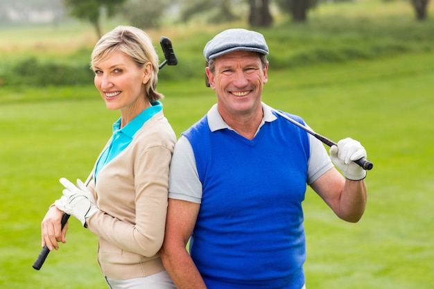 Casal de golfe sorrindo para a câmera no putting green