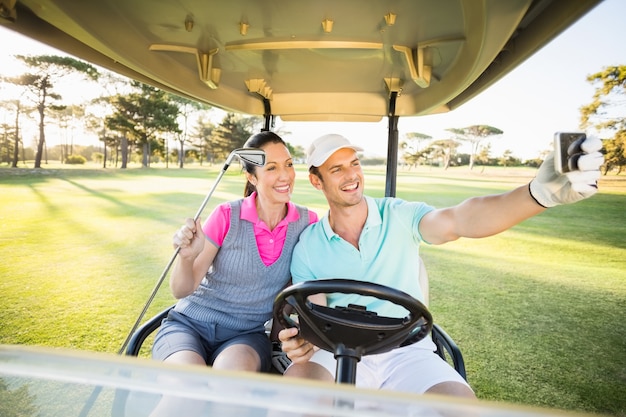 Casal de golfista sorridente tendo auto-retrato