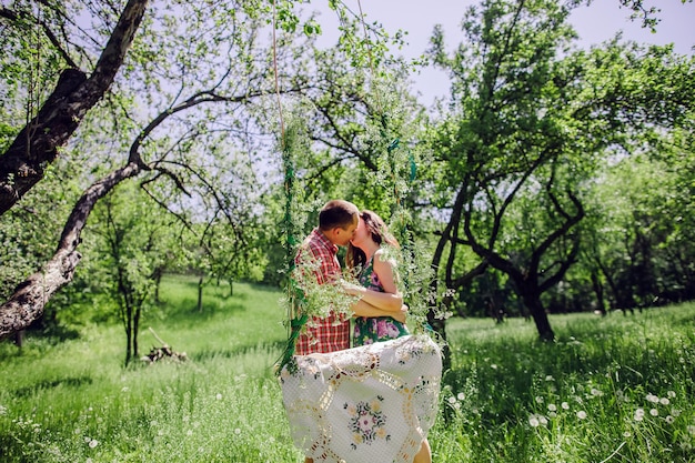 Foto casal de história de amor vintage. casal relaxa no prado verde e jardim. balanço de fundo.