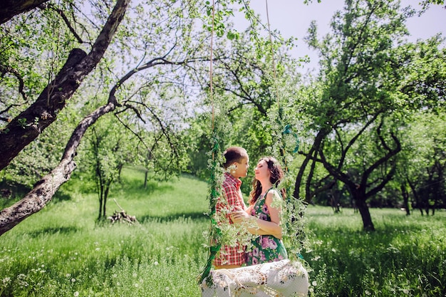 Foto casal de história de amor vintage. casal relaxa no prado verde e jardim. balanço de fundo.