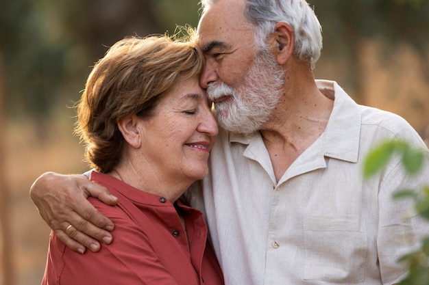 Foto casal de idosos abraçados romanticamente em seu jardim rural