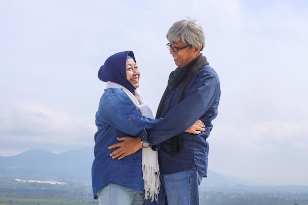 Casal de idosos asiáticos Casal romântico sênior se encara e sorri sobre a bela paisagem