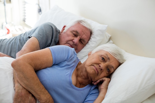 Casal de idosos dormindo no quarto de casa