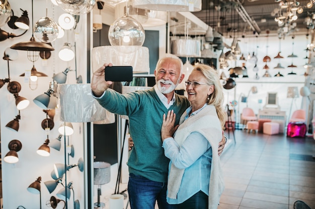 Casal de idosos em loja de iluminação doméstica fotografando o shandelier para sua casa