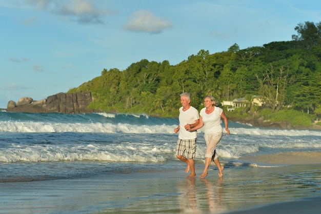 Casal de idosos feliz correndo na praia