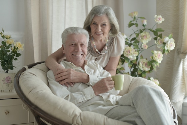 casal de idosos feliz descansando em casa com uma xícara de chá