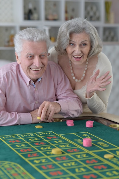 Casal de idosos feliz jogando com fichas de cassino