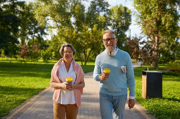 Foto casal de idosos felizes a fazer uma pausa para o café a passear no parque. homem e mulher idosos românticos que parecem felizes a desfrutar de um estilo de vida saudável na pensão