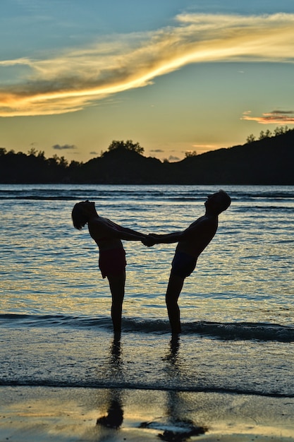 Casal de idosos felizes descansando em uma praia tropical ao pôr do sol