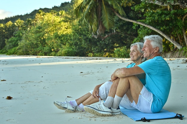 Casal de idosos felizes descansando em uma praia tropical