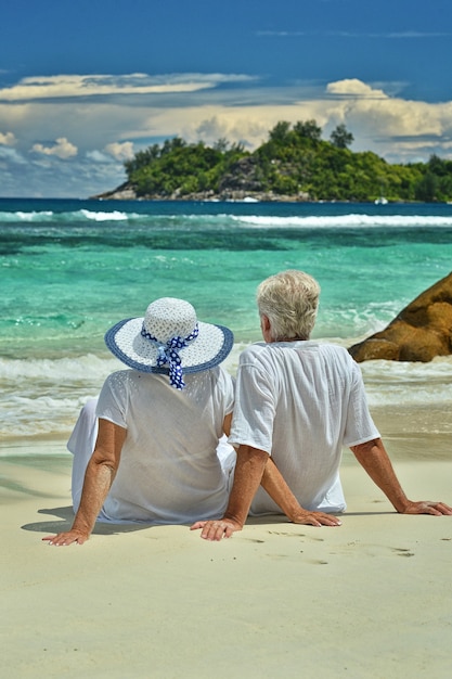 Casal de idosos felizes descansando em uma praia tropical