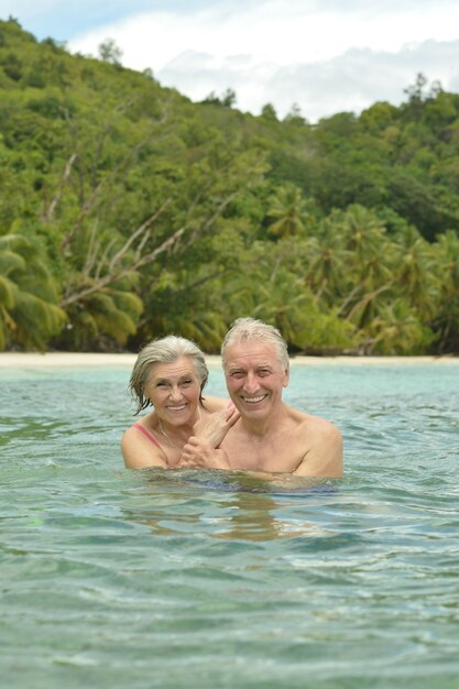 Casal de idosos felizes descansando em uma praia tropical