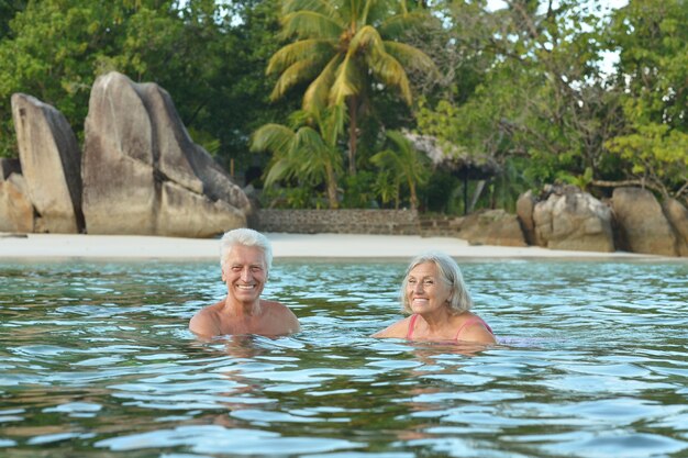 Foto casal de idosos felizes descansando em uma praia tropical