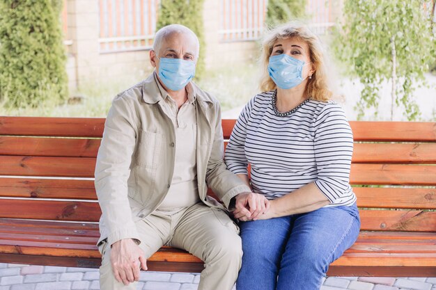 Casal de idosos idosos felizes usando máscara médica para proteger de coronavírus no parque de verão