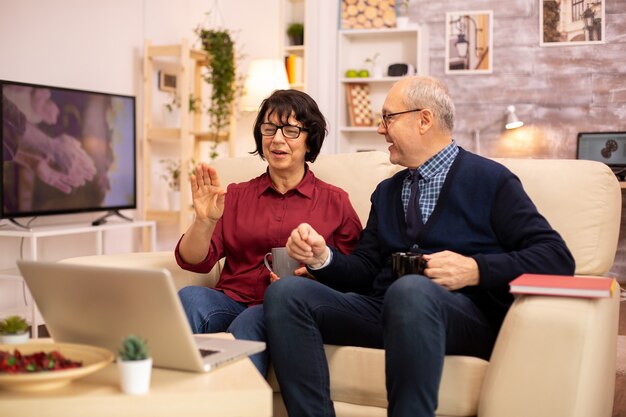 Casal de idosos idosos usando laptop moderno para conversar com seu neto. Avó e avô usando tecnologia moderna