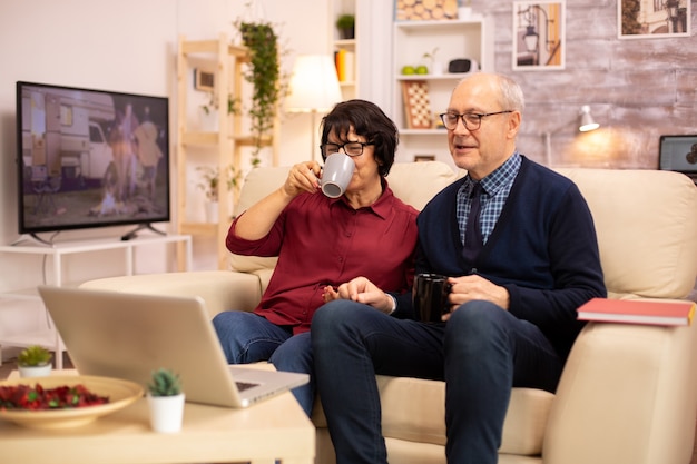 Casal de idosos idosos usando laptop moderno para conversar com seu neto. Avó e avô usando tecnologia moderna