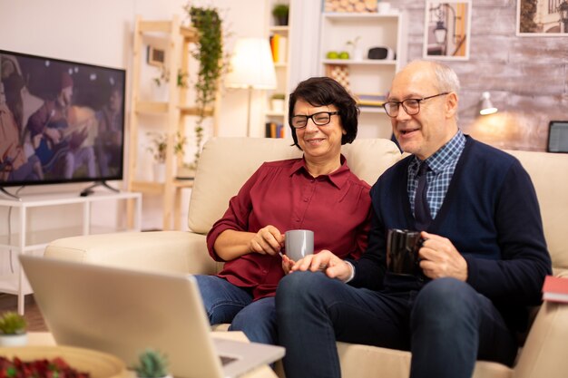 Casal de idosos idosos usando laptop moderno para conversar com seu neto. Avó e avô usando tecnologia moderna