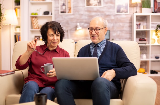 Casal de idosos idosos usando laptop moderno para conversar com seu neto. Avó e avô usando tecnologia moderna