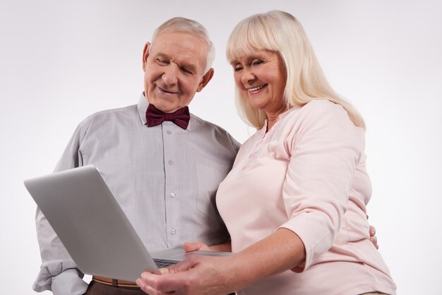 Casal de idosos interage com o laptop.