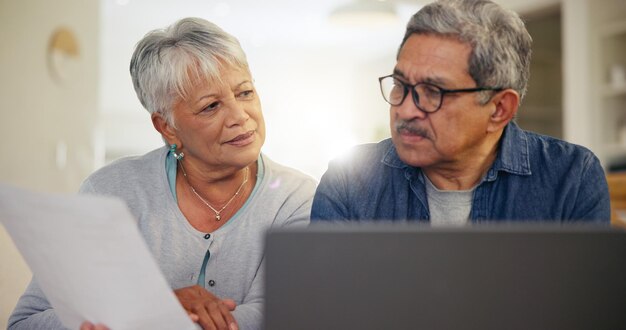 Casal de idosos portátil e documentos em casa para planejamento orçamental ativos financeiros ou carteira de investimentos Homem mulher e papelada no computador de empréstimo bancário poupança de aposentadoria ou apólice de seguro