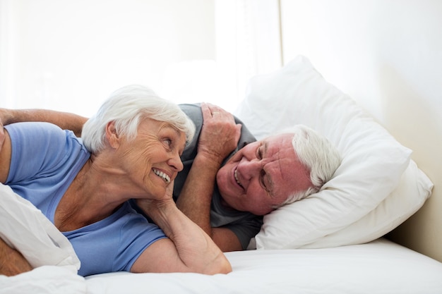 Casal de idosos relaxando no quarto em casa