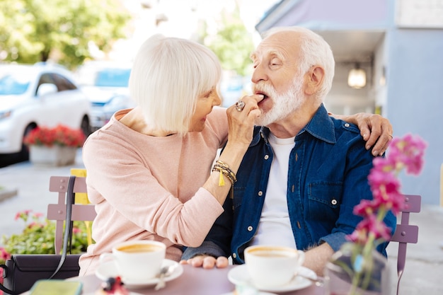 Casal de idosos satisfeito dançando e sentado em um café