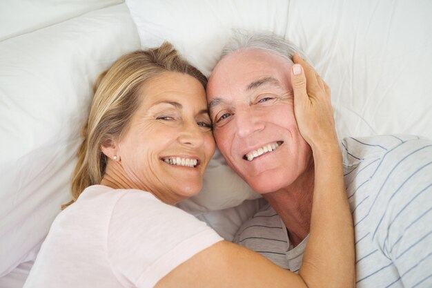 Casal de idosos se abraçando na cama