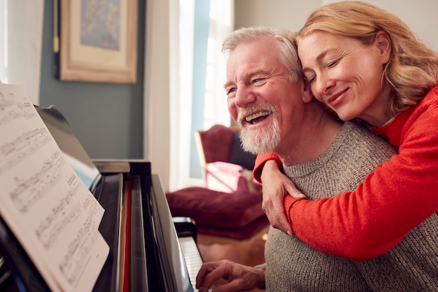 Casal de idosos sorridente em casa gostando de aprender a tocar piano