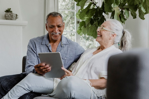 Casal de idosos usando tablet no sofá