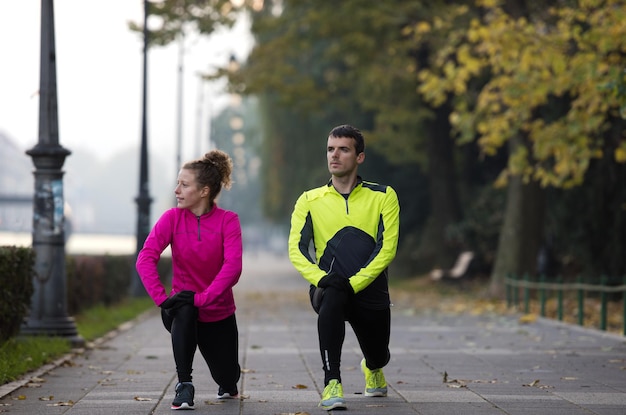 casal de jogging se aquecendo e se alongando antes da corrida matinal na cidade