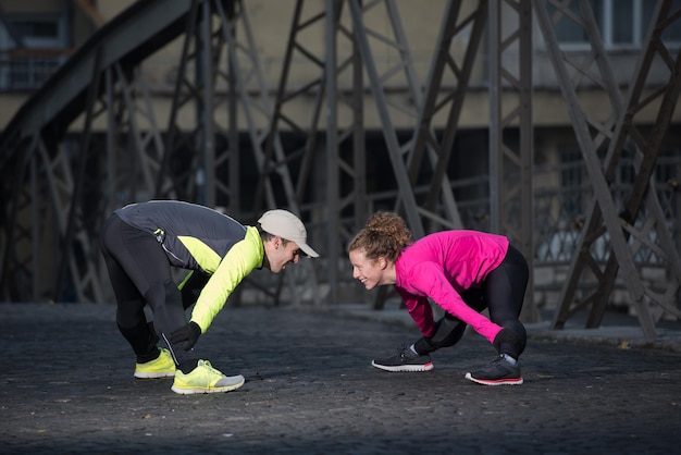 casal de jogging se aquecendo e se alongando antes da corrida matinal na cidade