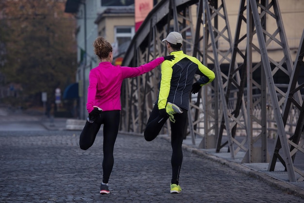 casal de jogging se aquecendo e se alongando antes da corrida matinal na cidade