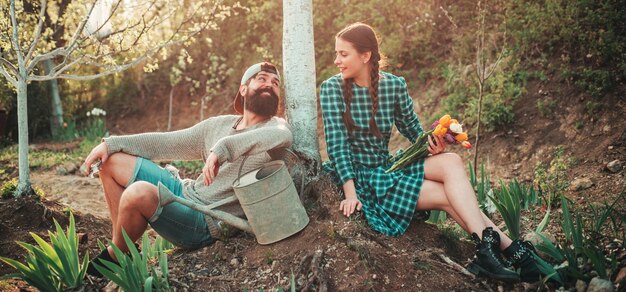 Casal de jovens agricultores no banner de primavera da fazenda eu amo nossos momentos na jardinagem de primavera do campo