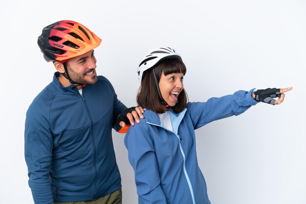 Casal de jovens ciclistas isolado no fundo branco apresentando uma ideia enquanto olha sorrindo para