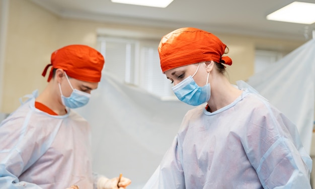 Casal de jovens cirurgiões trabalhando no hospital moderno Médico com assistência trabalhando juntos Foto Premium